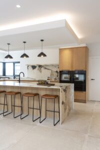 Verta oak cabinetry with built-in ovens beside the island